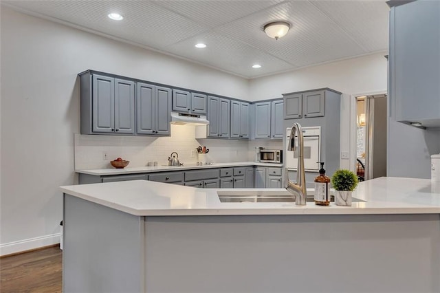 1772 Brittany Chase NW, Kennesaw, GA 30152 - kitchen with gray cabinetry, under cabinet range hood, a peninsula, recessed lighting, and dark wood-style flooring