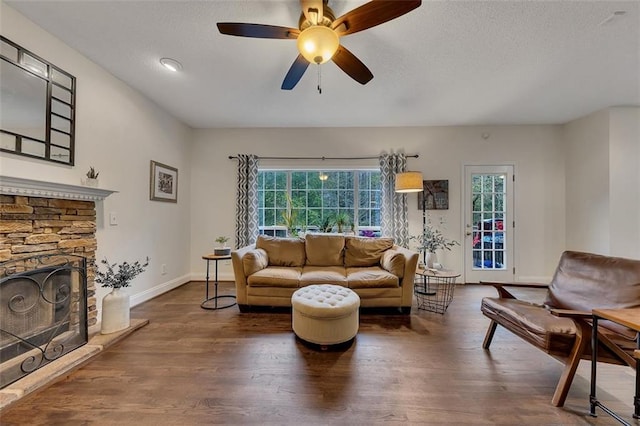 1772 Brittany Chase NW, Kennesaw, GA 30152 - living room with baseboards, wood finished floors, a ceiling fan, a stone fireplace, and a textured ceiling