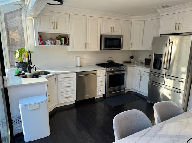 kitchen with sink, white cabinets, dark wood-type flooring, light stone counters, and stainless steel appliances