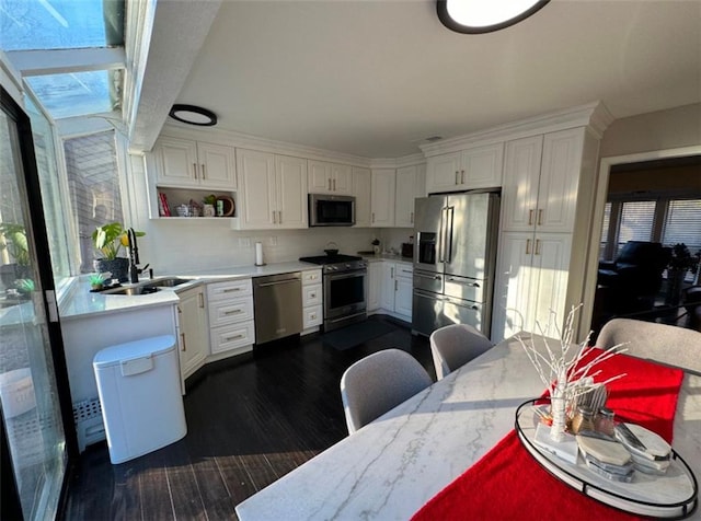 kitchen with a kitchen breakfast bar, dark hardwood / wood-style flooring, sink, appliances with stainless steel finishes, and white cabinetry