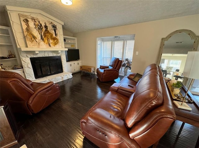 living room featuring a textured ceiling, a stone fireplace, a healthy amount of sunlight, vaulted ceiling, and hardwood / wood-style flooring