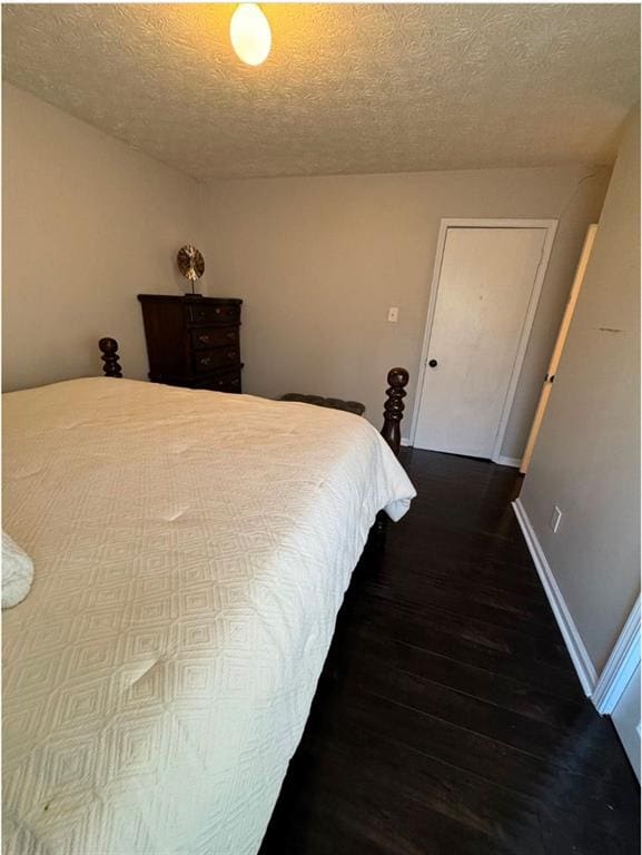 bedroom with dark hardwood / wood-style floors and a textured ceiling