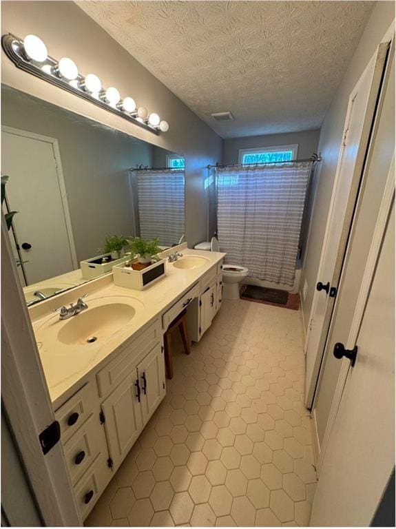 full bathroom with vanity, toilet, shower / bath combo with shower curtain, and a textured ceiling