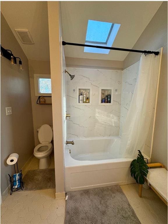 bathroom featuring shower / bathtub combination with curtain, toilet, tile patterned flooring, and a skylight