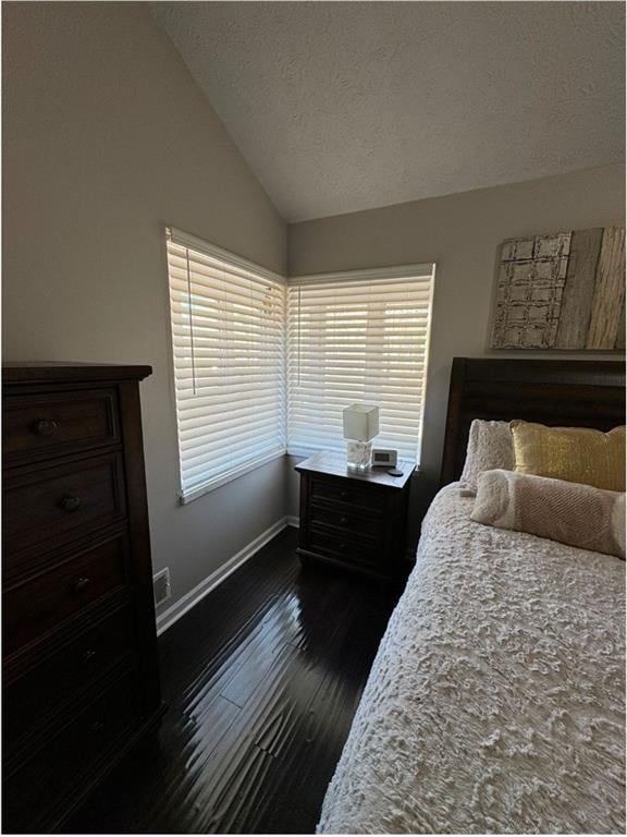 bedroom featuring a textured ceiling, dark hardwood / wood-style flooring, and lofted ceiling