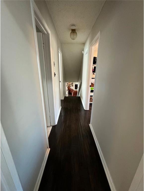 hallway featuring a textured ceiling and dark hardwood / wood-style flooring