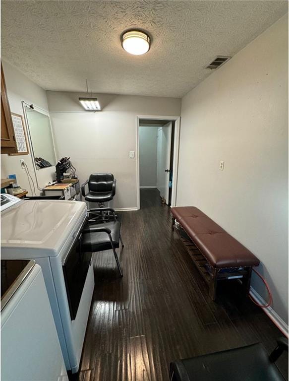 laundry room with washer and clothes dryer, dark wood-type flooring, and a textured ceiling