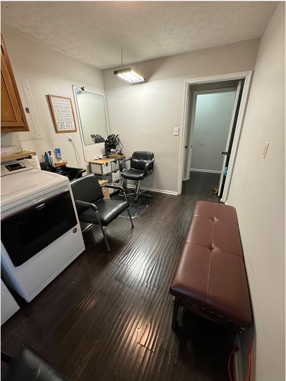 bedroom with dark wood-type flooring, a textured ceiling, and washer / clothes dryer