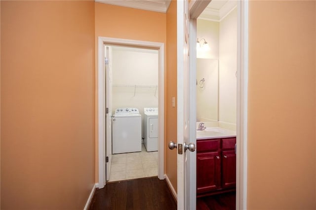 hall featuring baseboards, dark wood-style floors, ornamental molding, washing machine and clothes dryer, and a sink