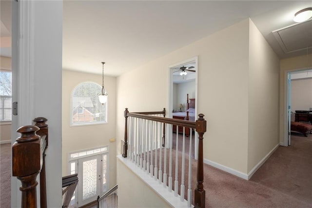 hallway with carpet, attic access, baseboards, and an upstairs landing