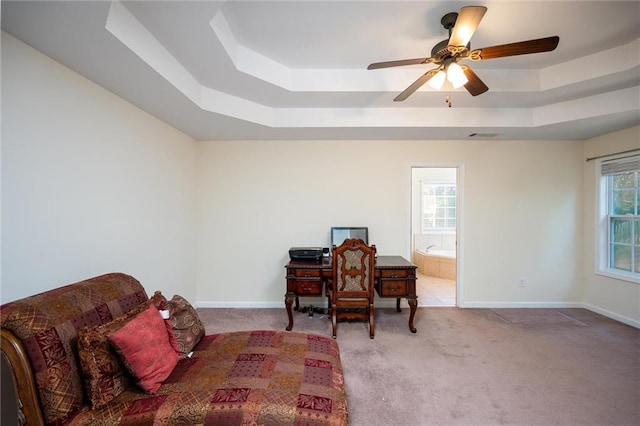 carpeted office with a tray ceiling, ceiling fan, and baseboards