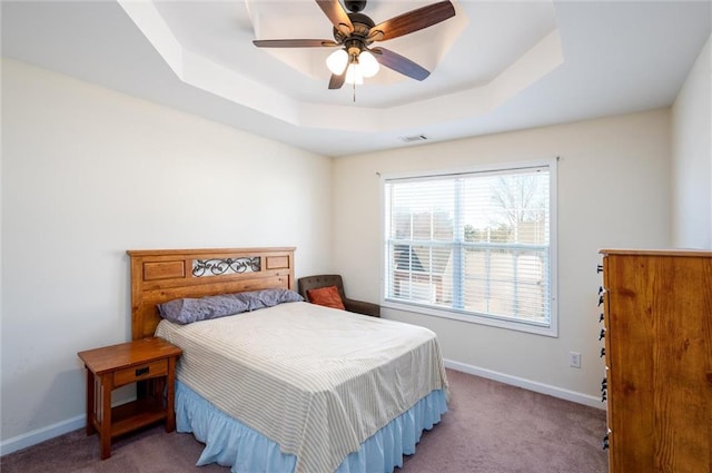 bedroom with a tray ceiling, carpet, and baseboards