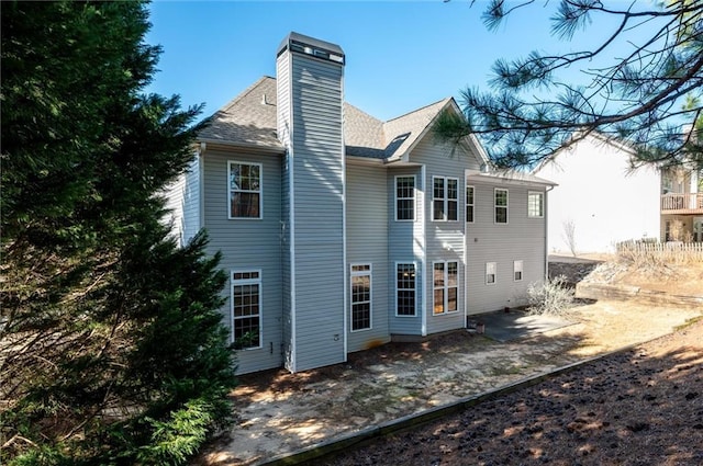 back of property featuring roof with shingles and a chimney