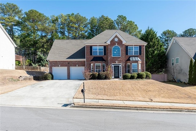 colonial inspired home with a garage, concrete driveway, brick siding, and fence