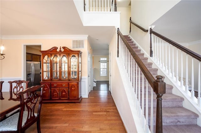 stairs featuring visible vents, crown molding, and wood finished floors