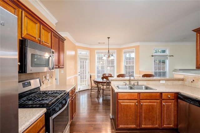 kitchen featuring appliances with stainless steel finishes, brown cabinets, dark wood-style flooring, light countertops, and a sink