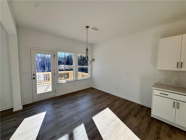 unfurnished dining area with dark hardwood / wood-style flooring and a notable chandelier