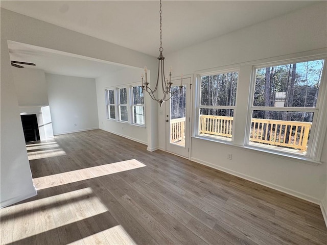 unfurnished dining area with hardwood / wood-style floors and ceiling fan with notable chandelier