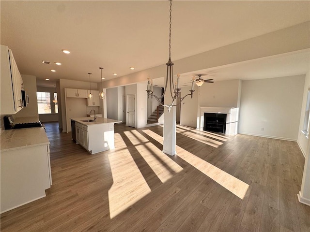 kitchen with pendant lighting, a center island with sink, sink, dark hardwood / wood-style flooring, and white cabinetry