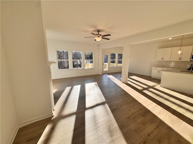 unfurnished living room featuring dark hardwood / wood-style floors, ceiling fan, and sink