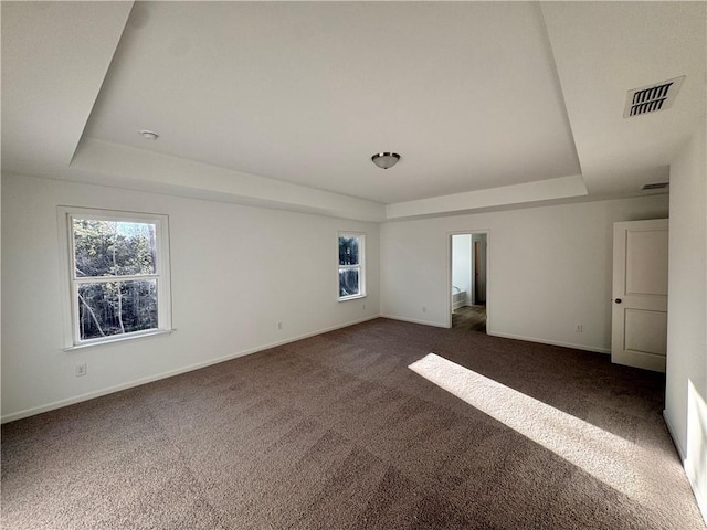 unfurnished bedroom featuring a tray ceiling and dark carpet