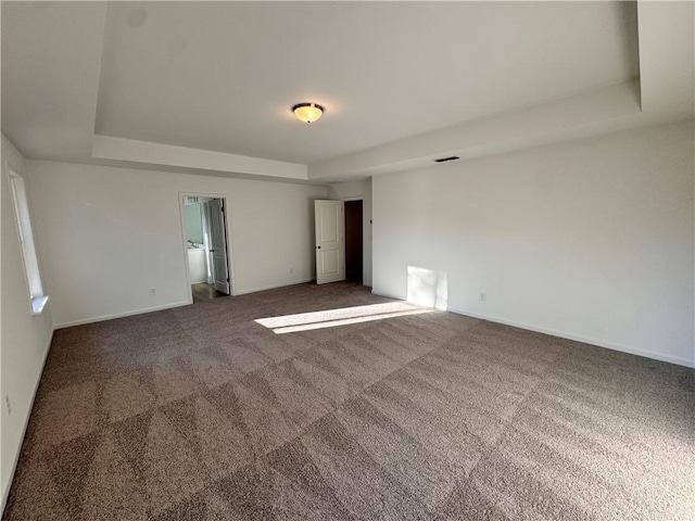 spare room featuring dark carpet and a tray ceiling