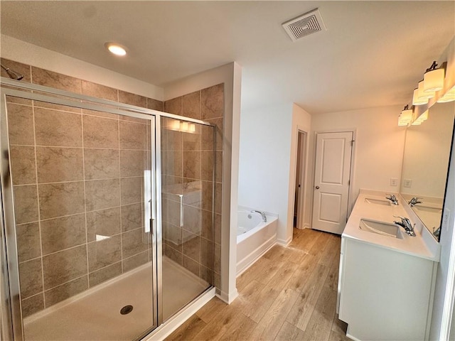 bathroom with hardwood / wood-style floors, vanity, and shower with separate bathtub