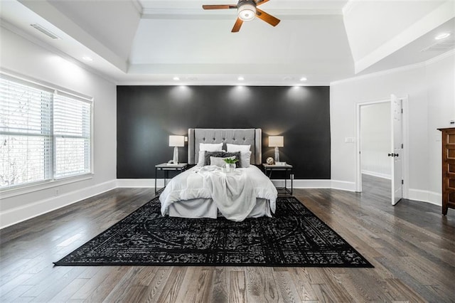 bedroom featuring crown molding, dark hardwood / wood-style floors, a raised ceiling, and ceiling fan