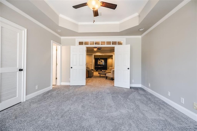 unfurnished bedroom with crown molding, ceiling fan, a tray ceiling, and carpet