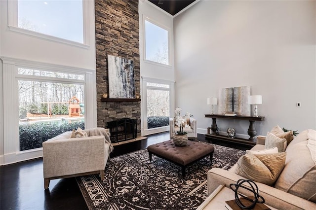 living room featuring hardwood / wood-style flooring, a towering ceiling, and a fireplace