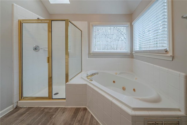 bathroom with a whirlpool tub, a stall shower, a skylight, and wood finished floors