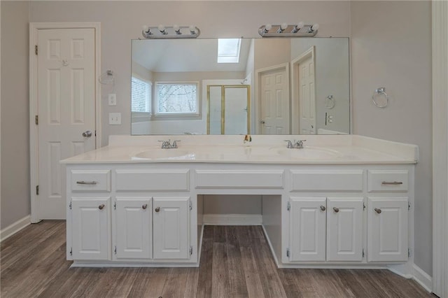 full bathroom with double vanity, wood finished floors, a stall shower, and a sink