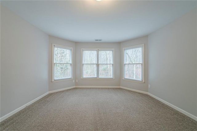 empty room with baseboards, light carpet, visible vents, and a healthy amount of sunlight