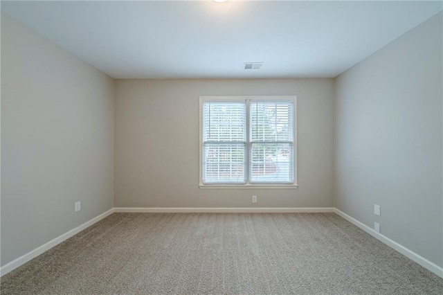 carpeted spare room with visible vents and baseboards