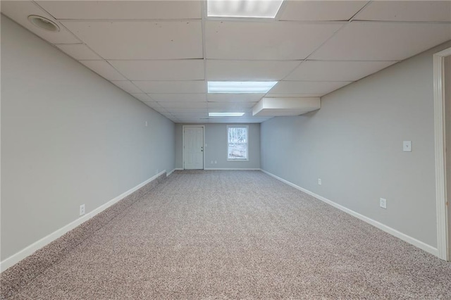 below grade area featuring carpet floors, a drop ceiling, and baseboards