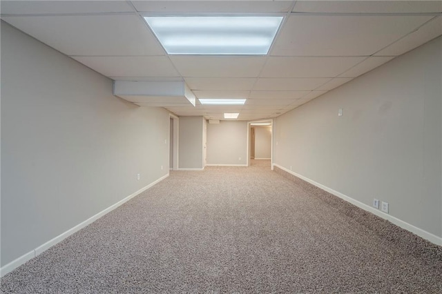 finished basement with carpet floors, a paneled ceiling, and baseboards