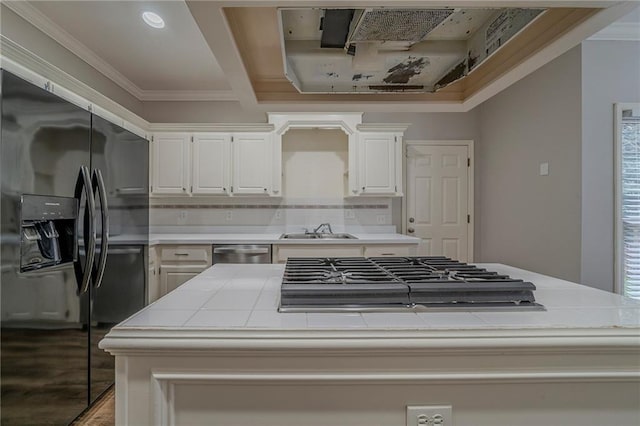 kitchen with decorative backsplash, appliances with stainless steel finishes, ornamental molding, white cabinets, and a sink