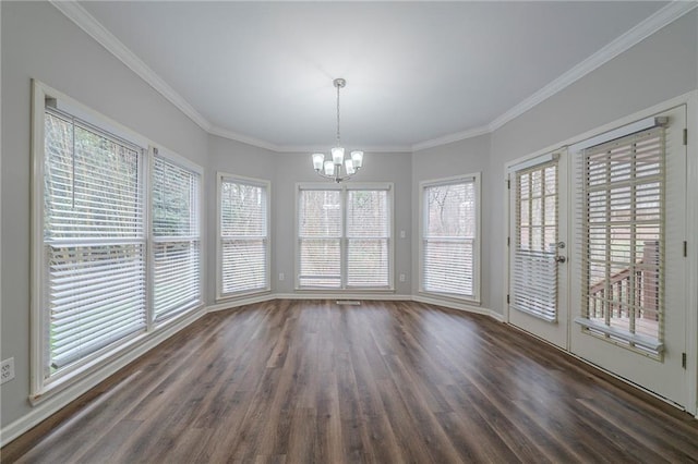 unfurnished dining area featuring dark wood-style floors, crown molding, baseboards, and an inviting chandelier