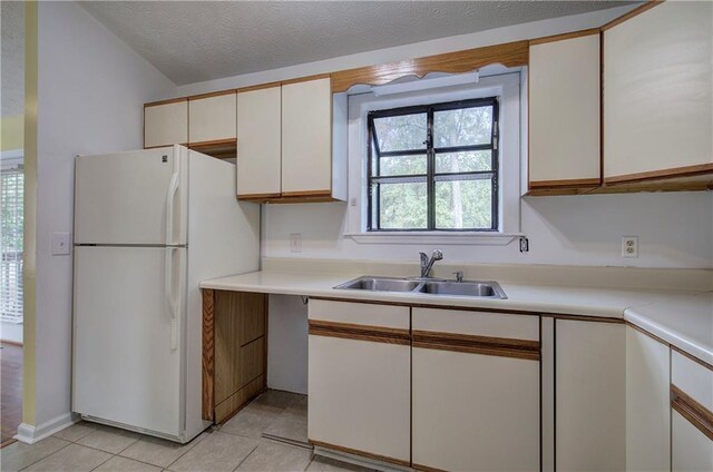 kitchen featuring white cabinets, a textured ceiling, sink, light tile patterned flooring, and white fridge