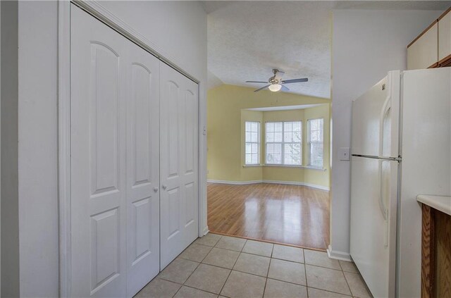 kitchen featuring ceiling fan, a textured ceiling, lofted ceiling, white fridge, and light wood-type flooring