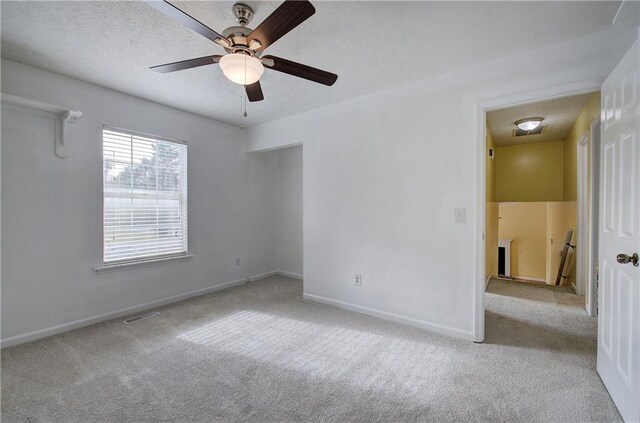 spare room featuring ceiling fan, a textured ceiling, and light carpet