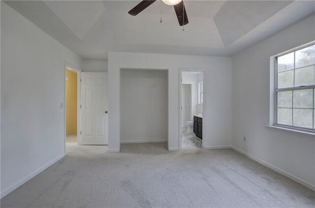 unfurnished bedroom with lofted ceiling, light carpet, ceiling fan, and ensuite bath