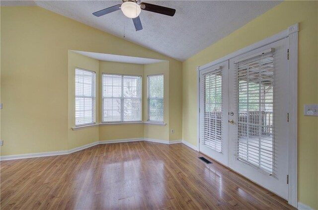 unfurnished room featuring light wood-type flooring, a wealth of natural light, and lofted ceiling