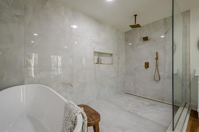bathroom featuring a marble finish shower and a freestanding tub