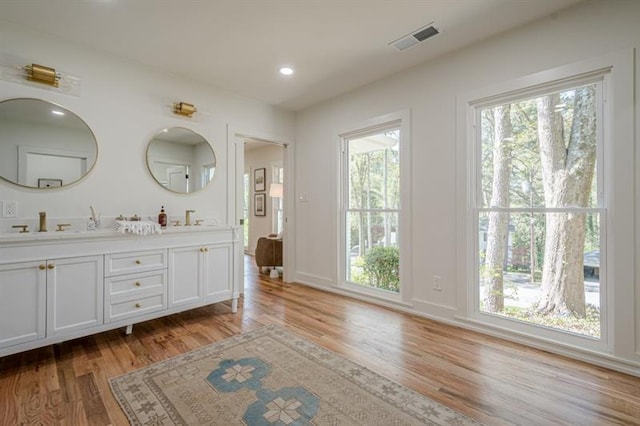 bathroom featuring recessed lighting, visible vents, a sink, double vanity, and wood finished floors