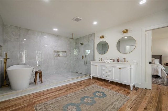 full bathroom featuring visible vents, a soaking tub, double vanity, wood finished floors, and a marble finish shower