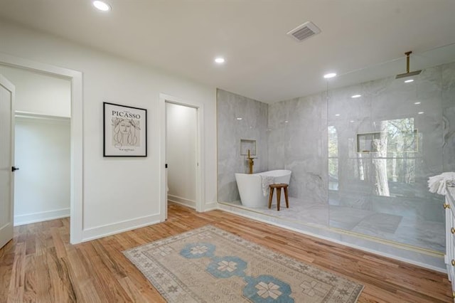 bathroom with a freestanding bath, a marble finish shower, visible vents, and wood finished floors