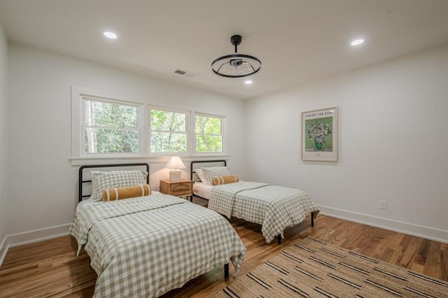 bedroom with baseboards, recessed lighting, visible vents, and wood finished floors