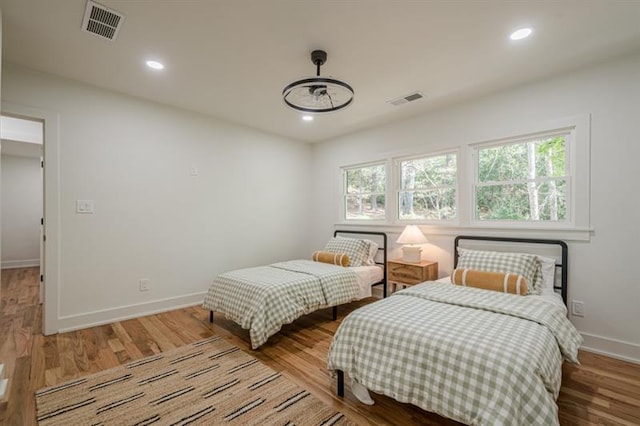 bedroom with baseboards, visible vents, and wood finished floors