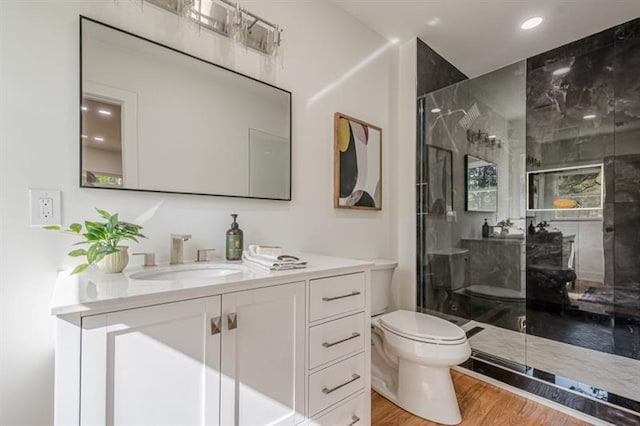 bathroom featuring toilet, wood finished floors, vanity, recessed lighting, and an enclosed shower